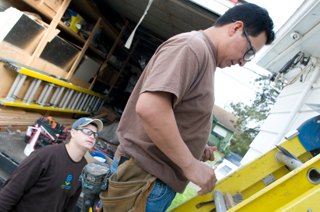 Two hispanic workers repairing the exterior of a house