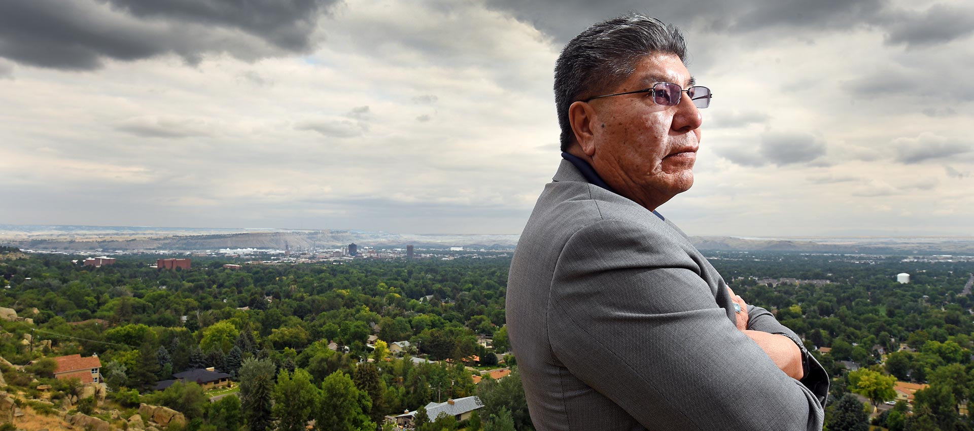 Native American man standing in front of landscape image of Northwest United States region