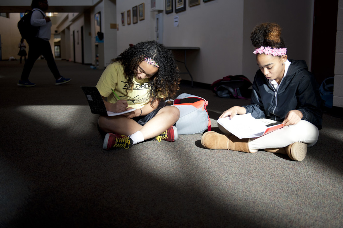 Two middle school girls studying in the school hallway